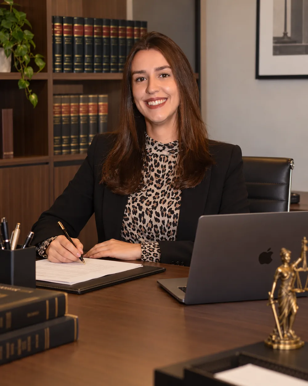 Marina Spina sorrindo à mesa do escritório, assinando um documento